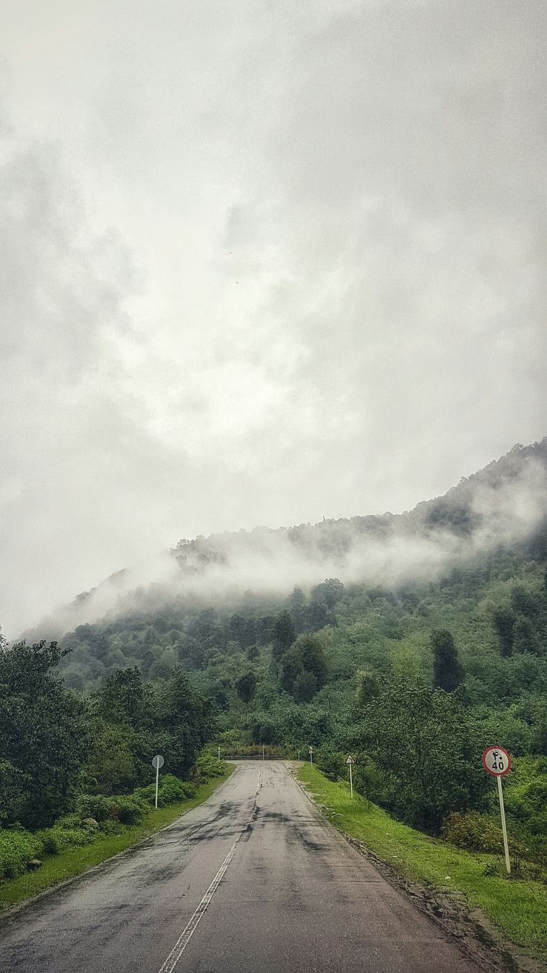 Carretera entre montañas verdes y neblina en el norte de Irán